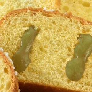 Close-up of a slice of bread with green jelly on a white background